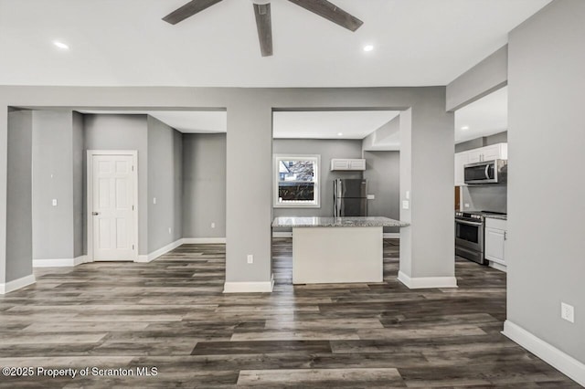 kitchen with appliances with stainless steel finishes, baseboards, white cabinets, and dark wood-type flooring