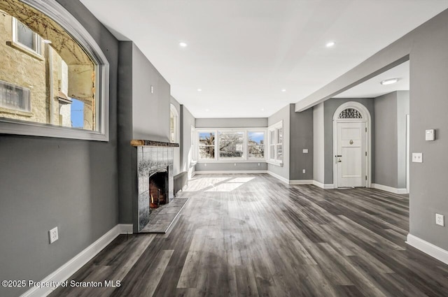 unfurnished living room with a tile fireplace, dark wood finished floors, baseboards, and recessed lighting