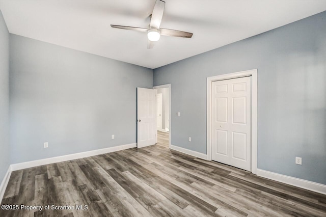 unfurnished bedroom with a ceiling fan, a closet, baseboards, and wood finished floors