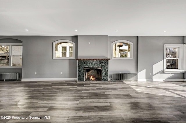 unfurnished living room featuring recessed lighting, a fireplace, radiator heating unit, and wood finished floors