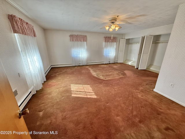 unfurnished bedroom featuring two closets, carpet floors, ceiling fan, and baseboard heating