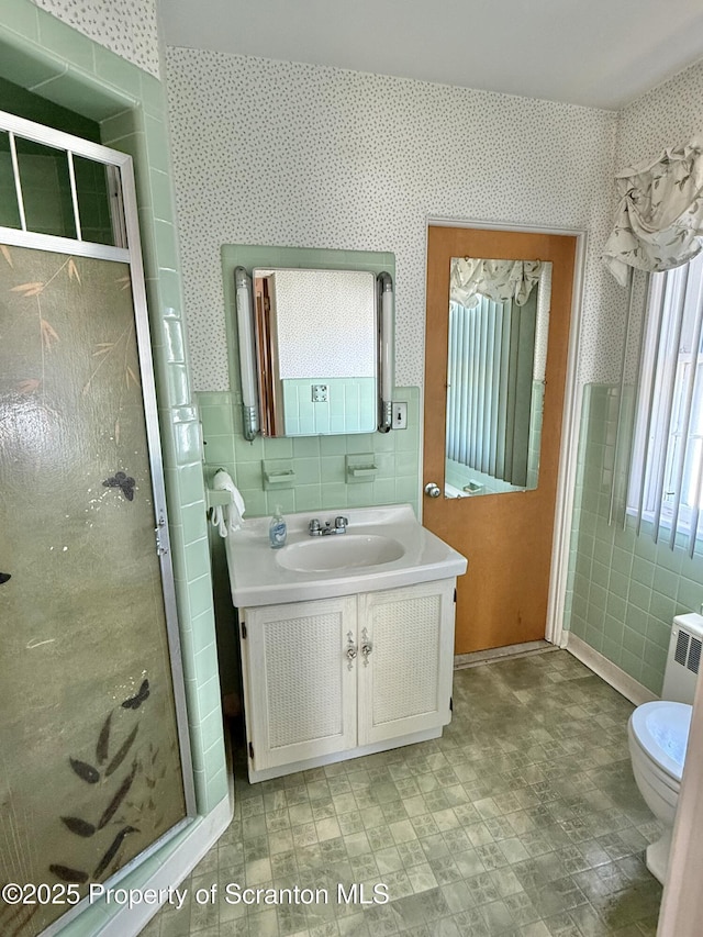 bathroom with tile walls, radiator, vanity, and toilet