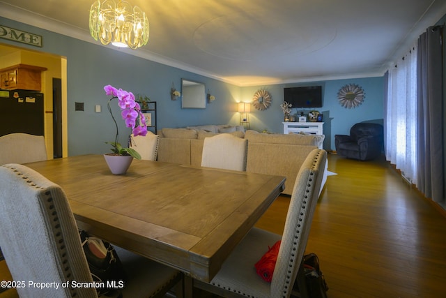 dining room with crown molding, a notable chandelier, and wood finished floors