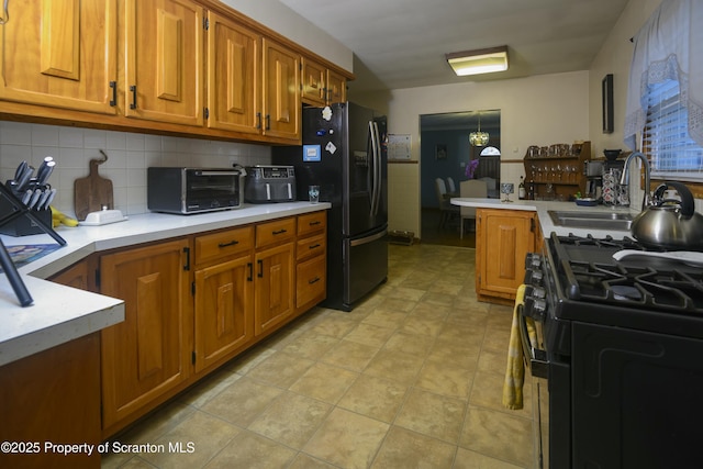 kitchen featuring a toaster, a sink, black appliances, light countertops, and brown cabinets