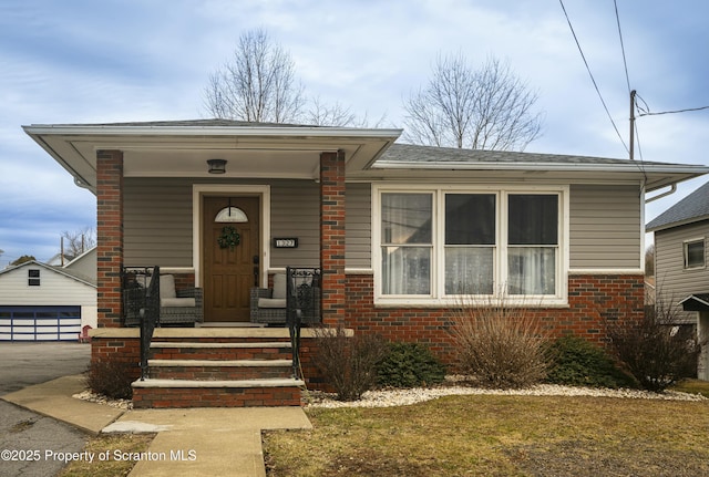 view of front of home with brick siding, covered porch, and an outdoor structure