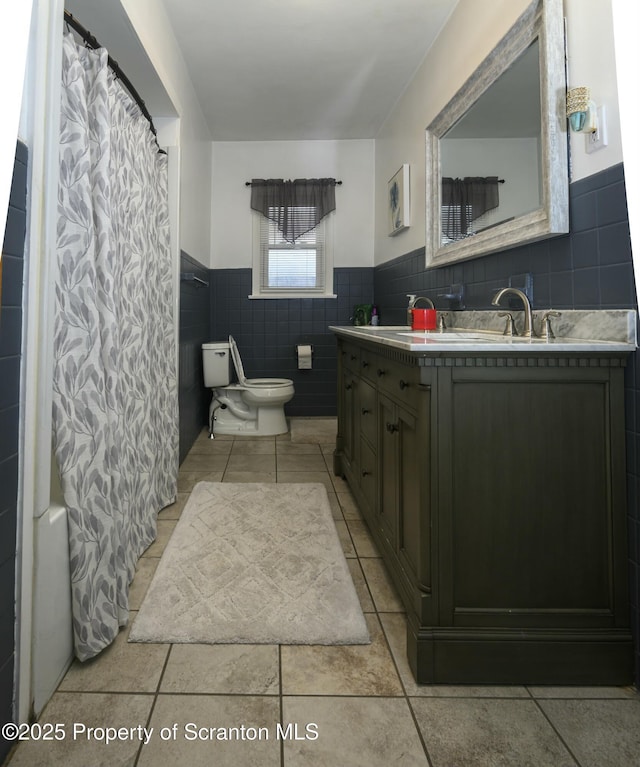 full bath featuring vanity, a shower with shower curtain, a wainscoted wall, tile patterned floors, and toilet