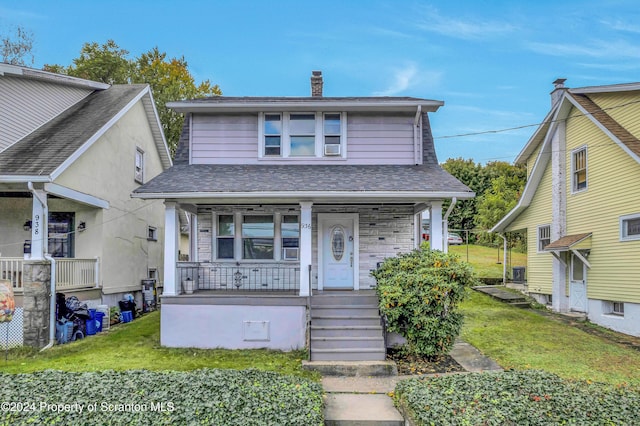 view of front facade with cooling unit, a porch, and a front yard