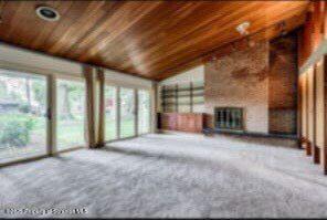 unfurnished living room with lofted ceiling, carpet flooring, and wooden ceiling