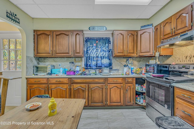 129-131 Main St, Dupont, PA 18641 - kitchen featuring stainless steel electric range, under cabinet range hood, light countertops, brown cabinets, and a paneled ceiling