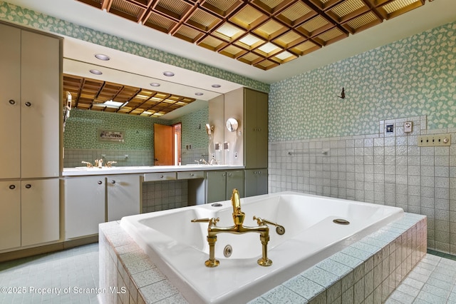 full bathroom with a tub with jets, wallpapered walls, recessed lighting, a sink, and tile patterned floors