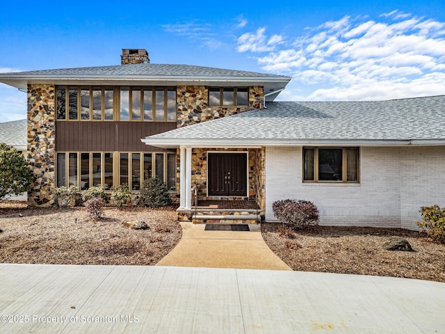 prairie-style house featuring brick siding, a chimney, roof with shingles, and a sunroom