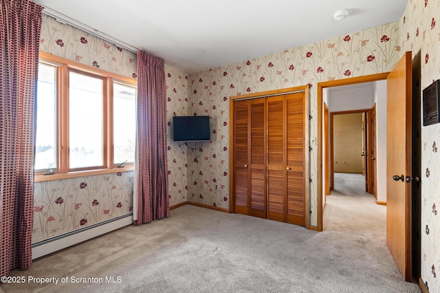 unfurnished bedroom featuring wallpapered walls, baseboards, carpet, baseboard heating, and a closet