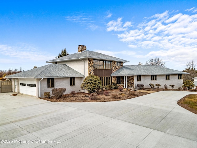 prairie-style home with an attached garage, a shingled roof, fence, a chimney, and driveway