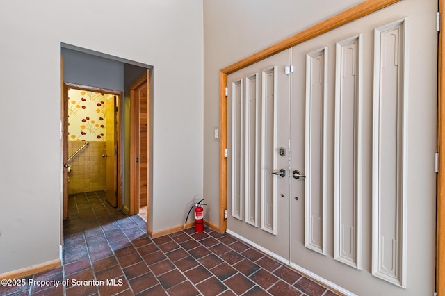 entryway with dark tile patterned flooring and baseboards