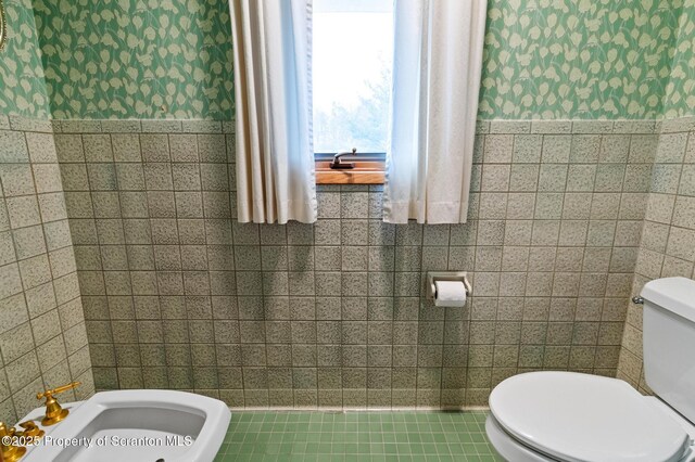 half bath featuring toilet and tile walls