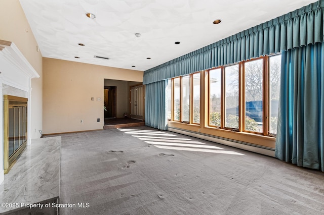 spare room featuring a glass covered fireplace, carpet, and visible vents