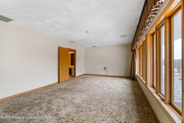 empty room with visible vents, baseboards, and carpet