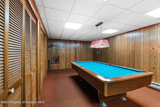 game room with a paneled ceiling, wood walls, and carpet flooring