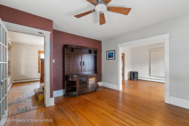 347 Orchard St, Old Forge, PA 18518 - unfurnished living room featuring wood-type flooring, baseboards, a ceiling fan, and baseboard heating
