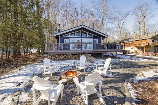 snow covered property featuring a wooden deck and an outdoor fire pit