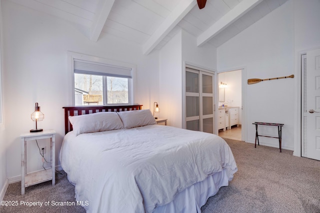 carpeted bedroom featuring vaulted ceiling with beams, ensuite bath, and ceiling fan