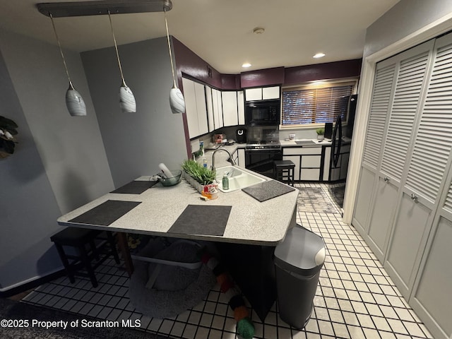 kitchen featuring pendant lighting, wall oven, a breakfast bar area, black microwave, and sink