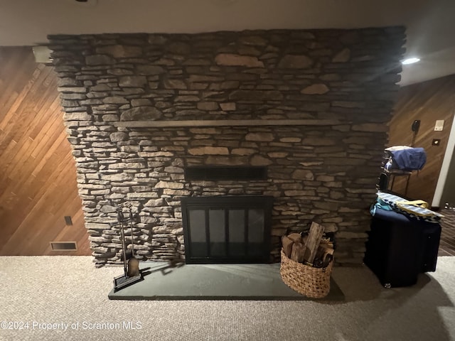 details featuring wood walls, a fireplace, and carpet flooring