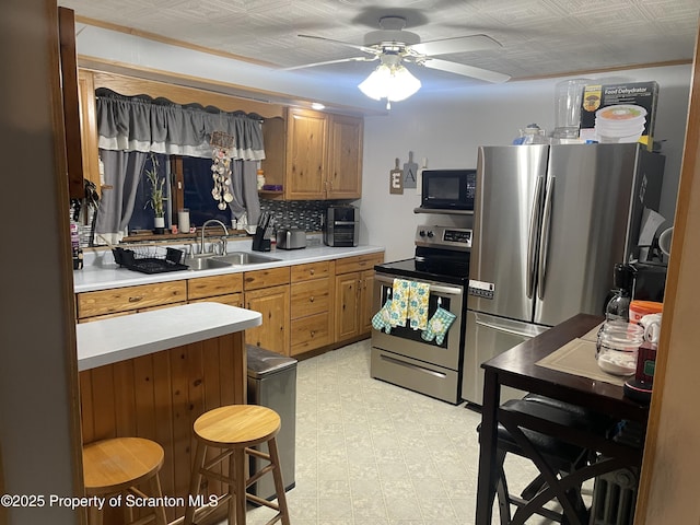 kitchen with appliances with stainless steel finishes, tasteful backsplash, sink, a kitchen breakfast bar, and ceiling fan