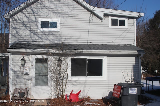 rear view of house featuring a shingled roof