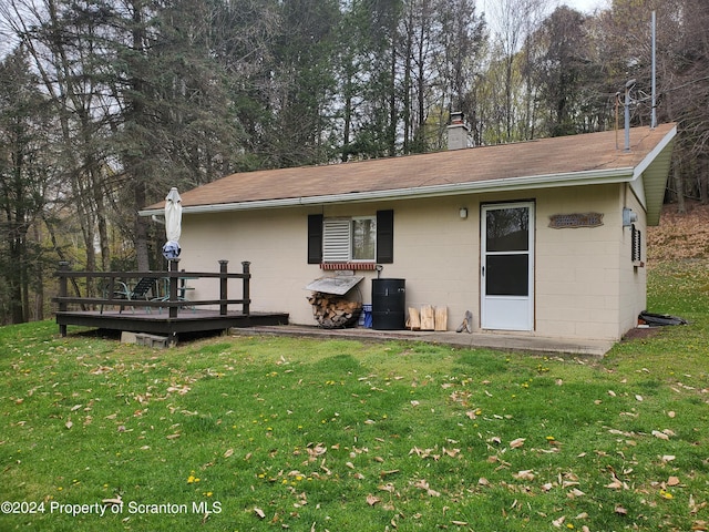 back of house featuring a lawn and a wooden deck