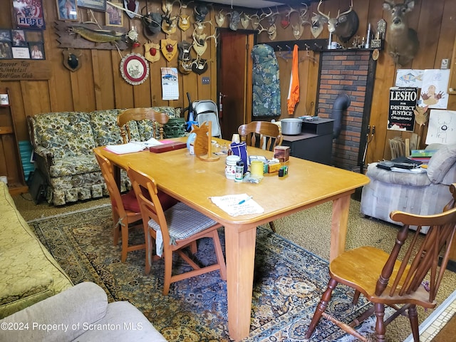 dining area with a wood stove and wooden walls