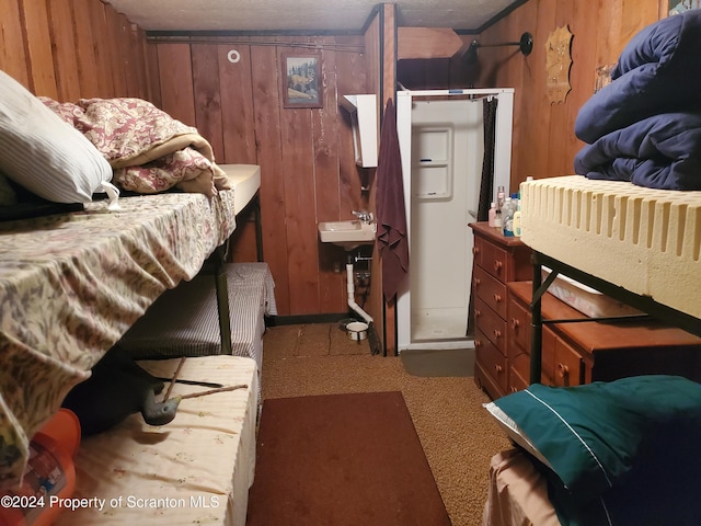 carpeted bedroom featuring wood walls