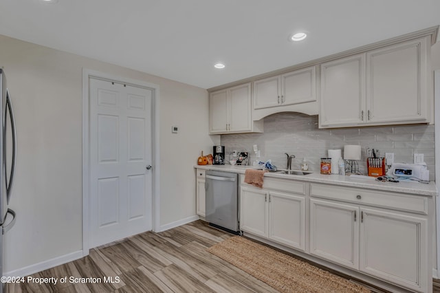 kitchen with backsplash, sink, light wood-type flooring, and stainless steel appliances