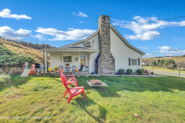 back of house featuring covered porch, ac unit, and a lawn