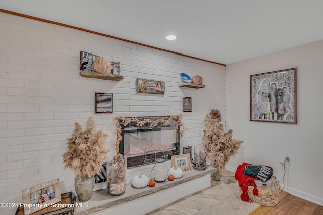 living room featuring a large fireplace, brick wall, and wood-type flooring