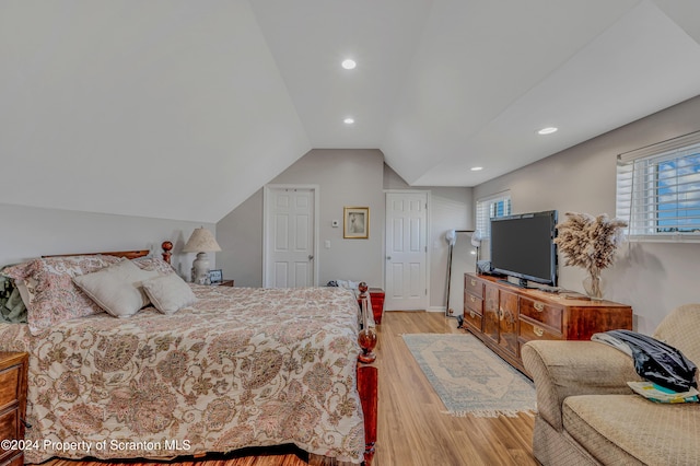 bedroom with light wood-type flooring and vaulted ceiling