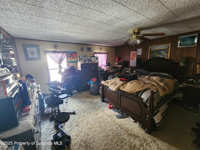 carpeted bedroom with a ceiling fan and wood walls