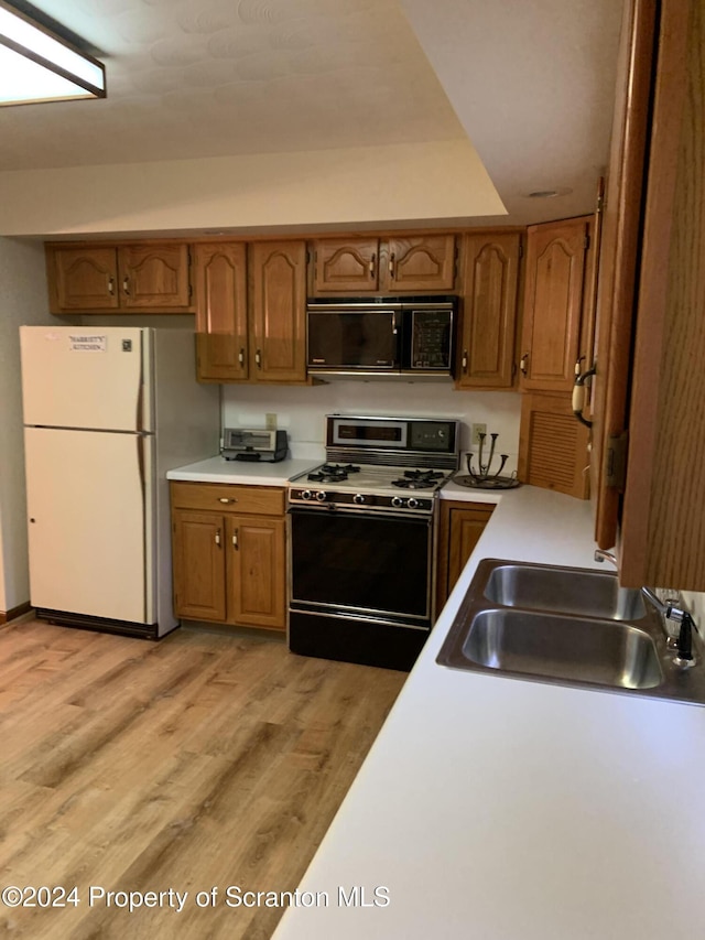 kitchen featuring sink, black appliances, and light hardwood / wood-style flooring