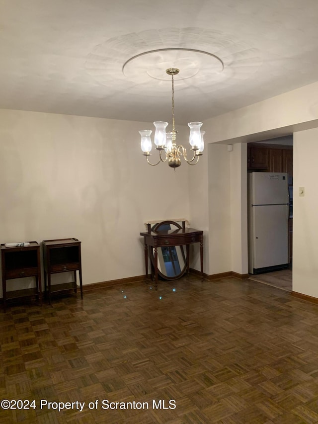 dining space with dark parquet flooring and an inviting chandelier