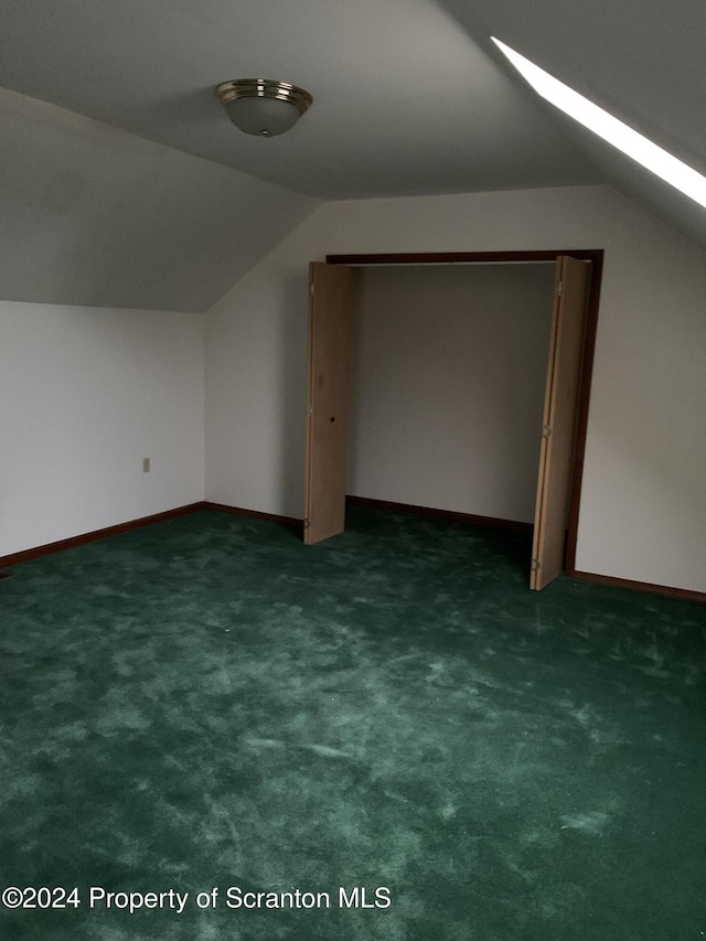 additional living space with dark colored carpet and vaulted ceiling