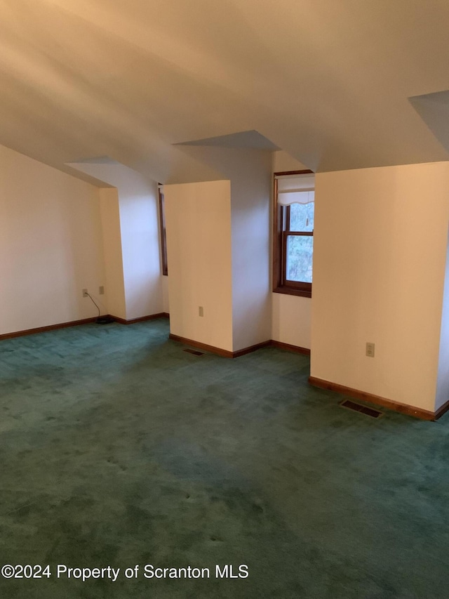 additional living space with dark carpet and vaulted ceiling