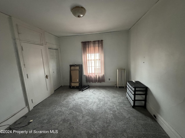 unfurnished bedroom with carpet floors, radiator, and a closet