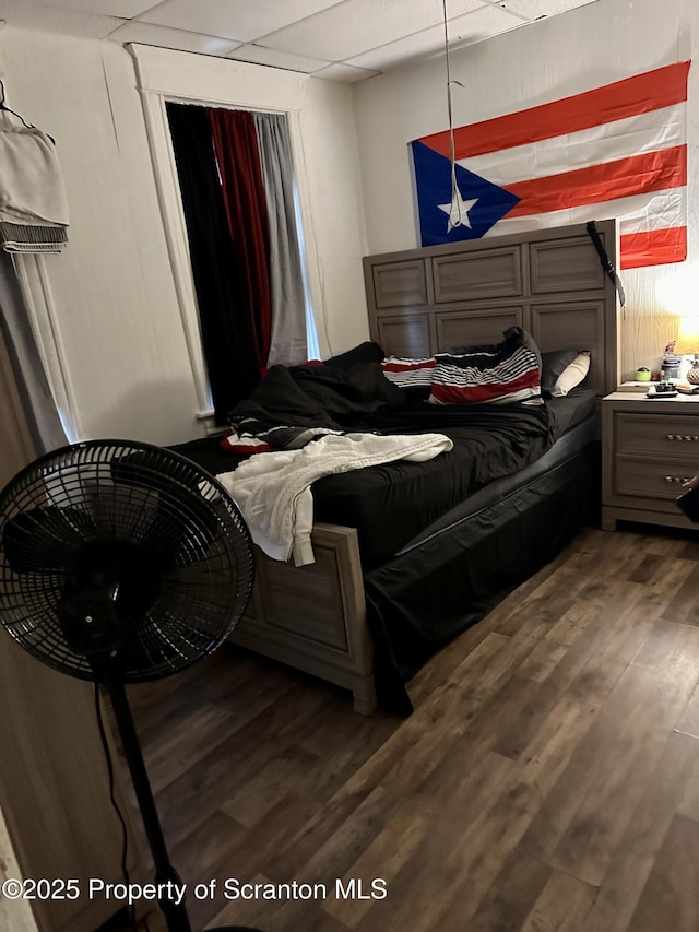 bedroom featuring dark wood-type flooring and a drop ceiling