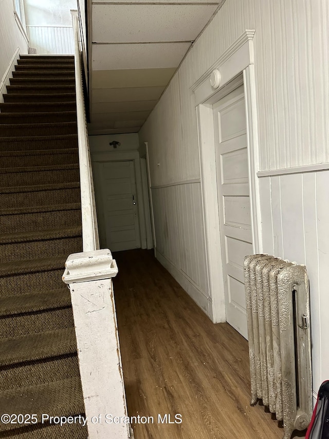 corridor with hardwood / wood-style floors and radiator heating unit