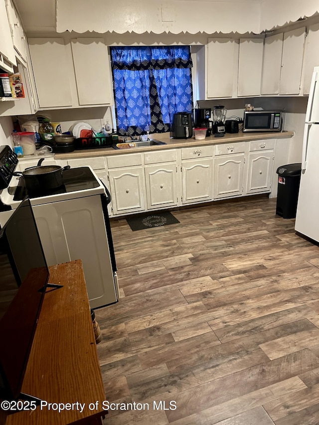 kitchen with white cabinetry, white fridge, sink, and range