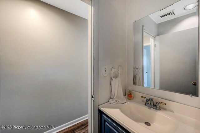 bathroom with wood finished floors, vanity, and baseboards
