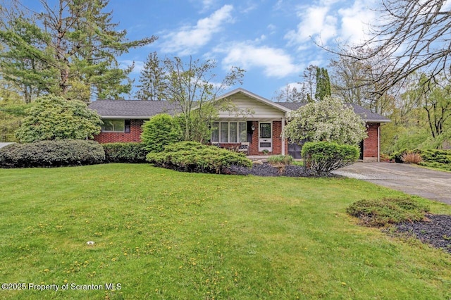single story home with brick siding, a front yard, and asphalt driveway