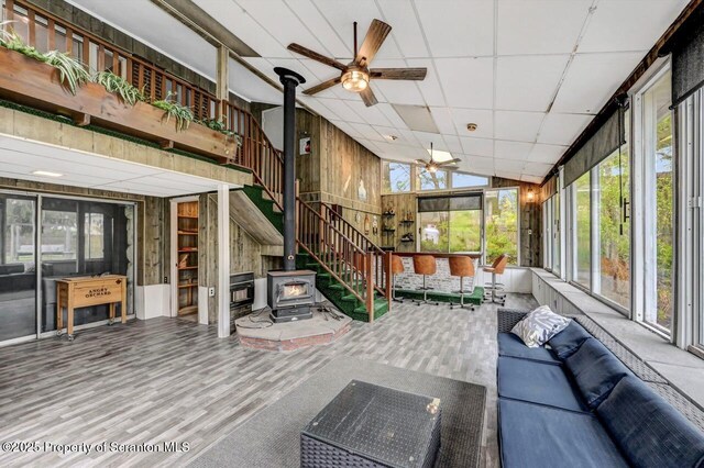 sunroom / solarium featuring a wood stove, an outdoor living space, ceiling fan, and lofted ceiling
