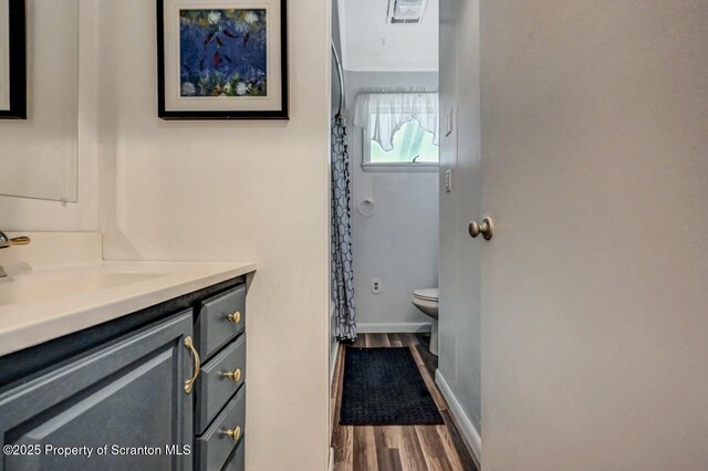 bathroom with vanity, toilet, wood finished floors, a shower with shower curtain, and baseboards