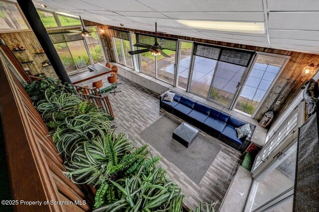 living area featuring ceiling fan and wood walls